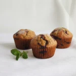 Chocolate Zucchini Muffins – Moist, Rich, and Easy to Bake 4 Chocolate zucchini muffins on a white surface
