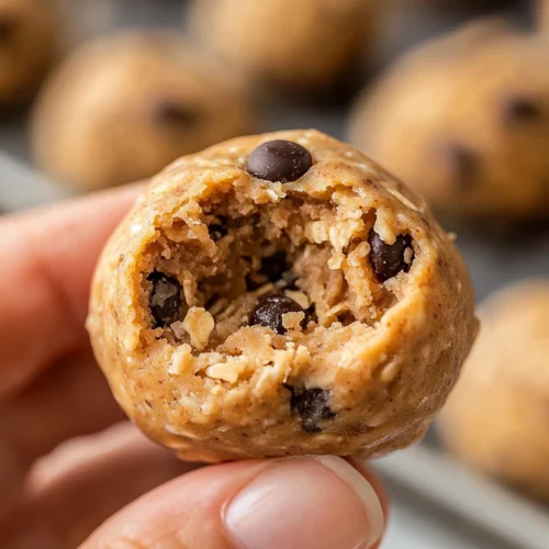 Protein Balls close-up: bitten peanut butter, oats, and chocolate chip energy bite held in hand.