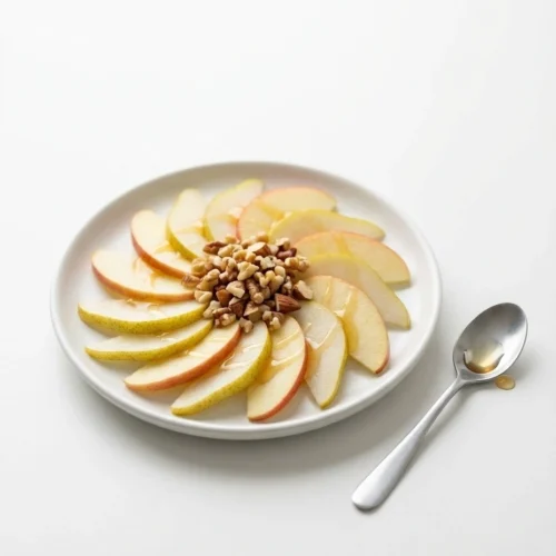 Fruit slices with nuts and a drizzle of Canaan honey on a small white plate.