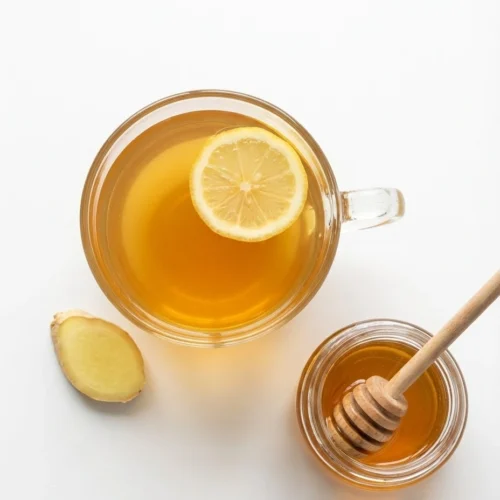 Overhead view of canaan honey trick drink with lemon and ginger on a white background.