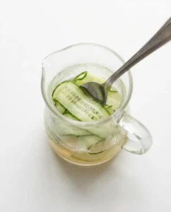 Cucumber slices in a small jug with kombucha as the base for a kombucha recipe for weight loss drink