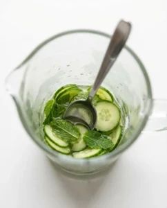 Cucumber and mint being muddled to prepare a spritzer that may ease kombucha side effects
