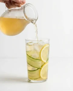 Cucumber lemon kombucha metabolism cooler being poured into a tall glass as a kombucha recipe for weight loss