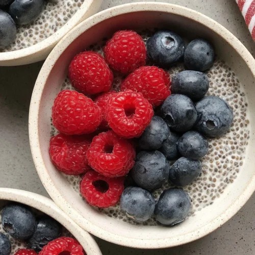 Oat milk chia pudding with berries in white bowls.