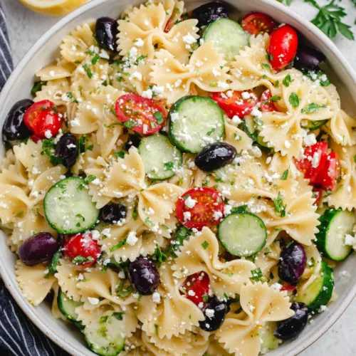 Colorful bow tie pasta salad with vegetables and feta.