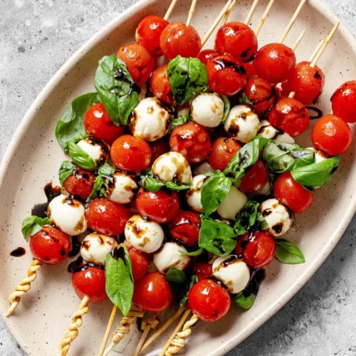 Caprese salad skewers with cherry tomatoes, mozzarella, and basil on a platter