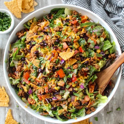 Chopped taco ground beef salad with vibrant vegetables and tortilla chips.
