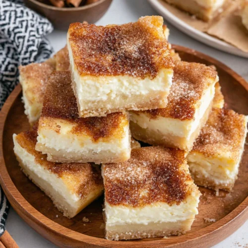 Crescent cheesecake bars topped with cinnamon sugar on a wooden plate.