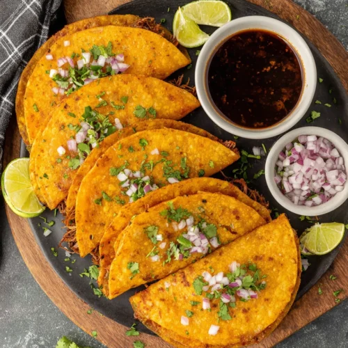 Enjoy savory crock pot birria tacos with vibrant garnishes.