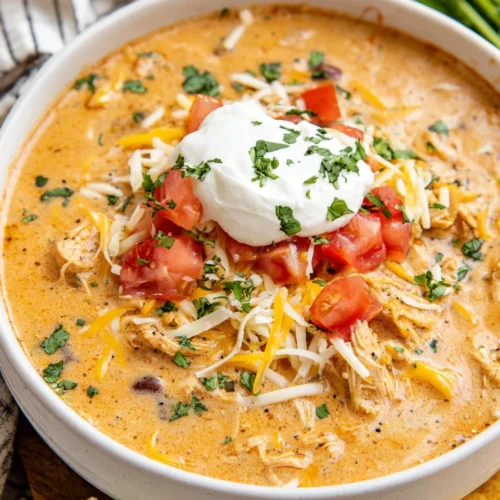 Easy chicken enchiladas soup garnished with cheese and tomatoes.