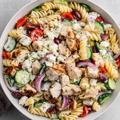 Healthy Greek chicken pasta salad with fresh veggies and dressing.