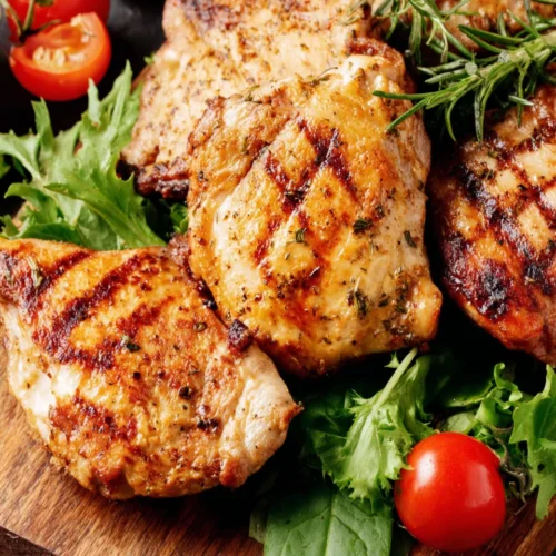 Grilled Greek marinated chicken thighs with fresh greens and tomato