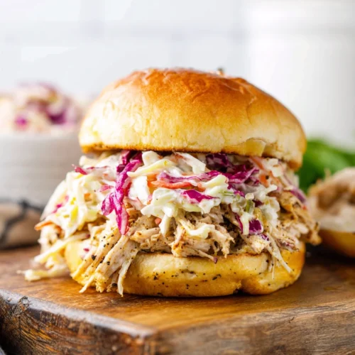 Jerk chicken sandwich with coleslaw on a wooden board