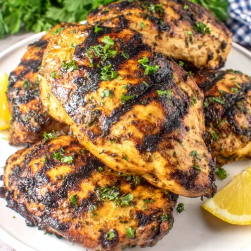 Mediterranean Grilled Chicken Breasts: Juicy and Flavorful Delight 1 Mediterranean grilled chicken breasts with herbs and lemon on a white plate