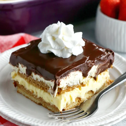 No-bake chocolate eclair cake slice with chocolate frosting and whipped cream