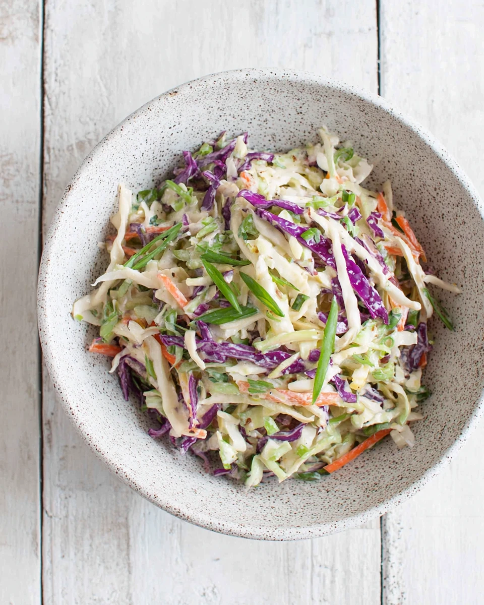 No mayo coleslaw with shredded cabbage, carrots, and scallions in a speckled bowl