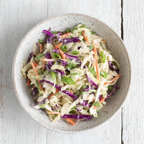 No mayo coleslaw with shredded cabbage, carrots, and scallions in a speckled bowl