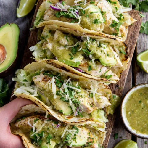 Salsa verde chicken tacos with toppings in a dish.