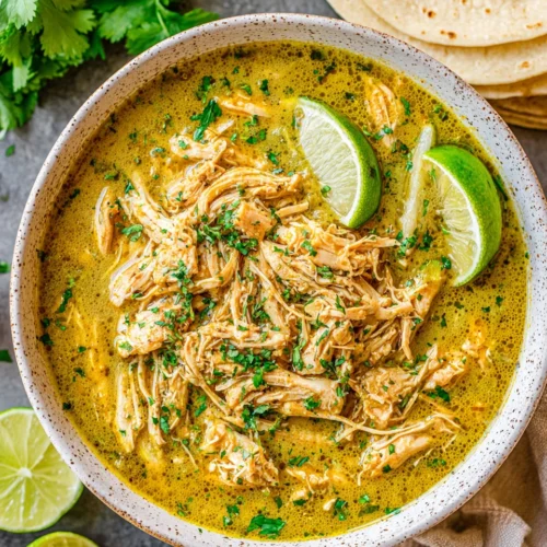 Slow cooker green chile chicken dish with lime slices.