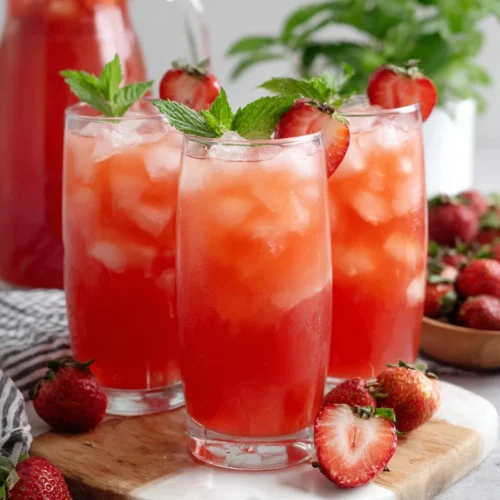 Refreshing agua de fresa in glasses with ice, strawberries, and mint garnish