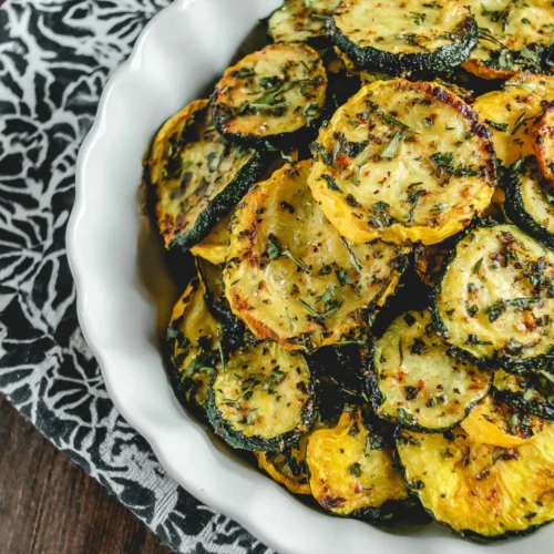 Air fryer yellow squash & zucchini in a white dish with herbs