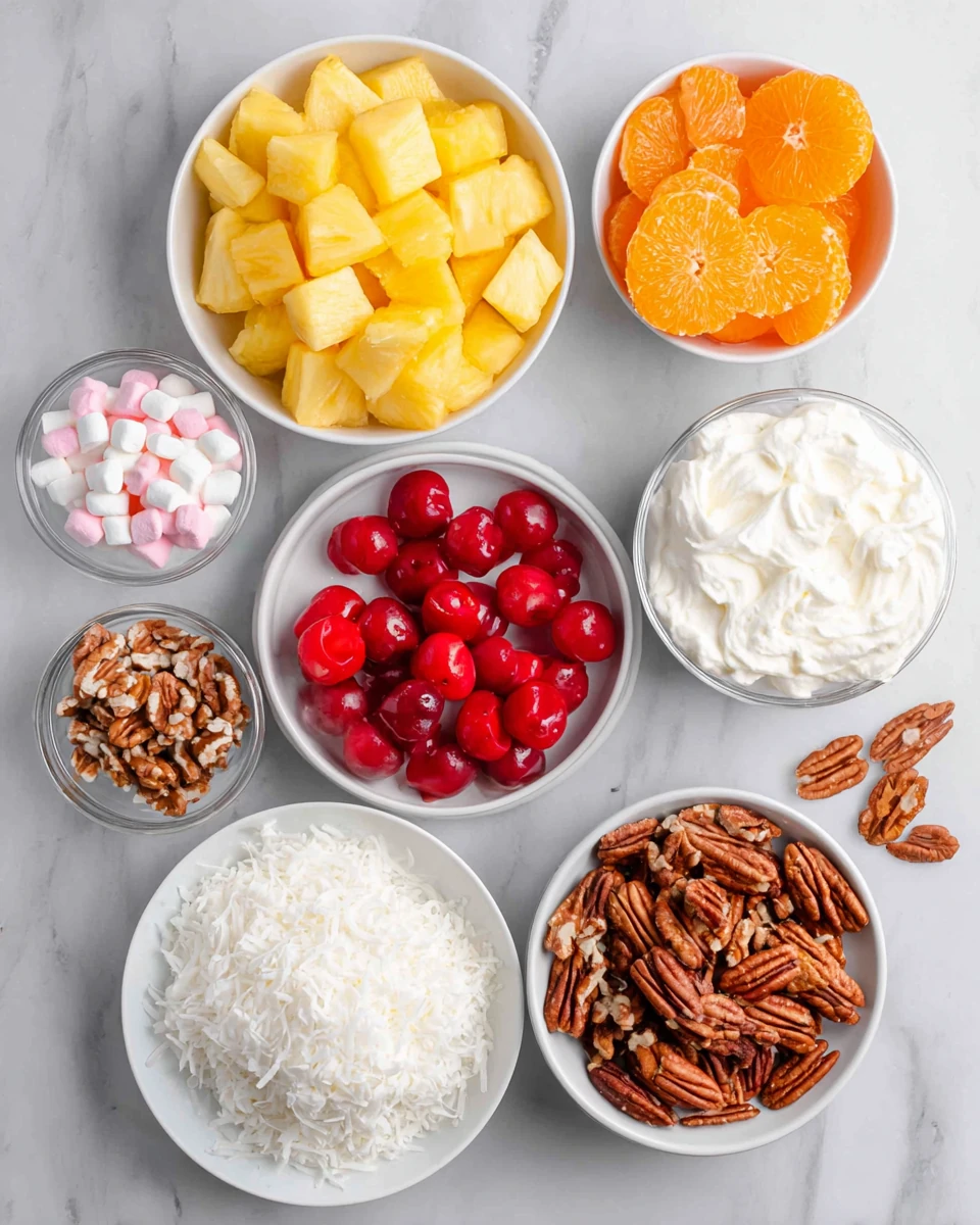 Ambrosia salad with Cool Whip ingredients: pineapple, oranges, cherries, marshmallows, coconut, pecans, and whipped topping