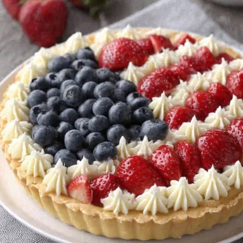 American flag fruit tart with strawberries and blueberries on a white plate
