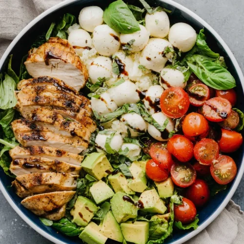 Balsamic chicken avocado caprese salad with grilled chicken, mozzarella, tomatoes, and avocado in a bowl