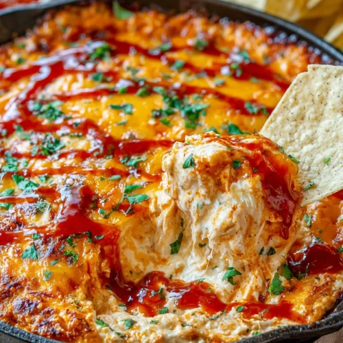 Creamy BBQ chicken dip with melted cheese and tortilla chip
