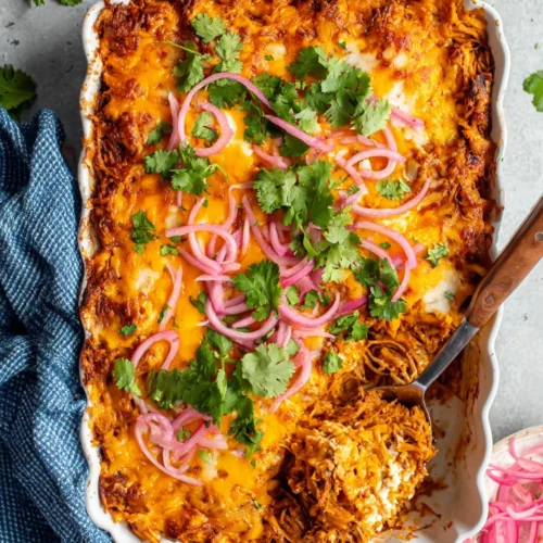 BBQ pulled pork casserole with melted cheese and pickled onions in a white dish