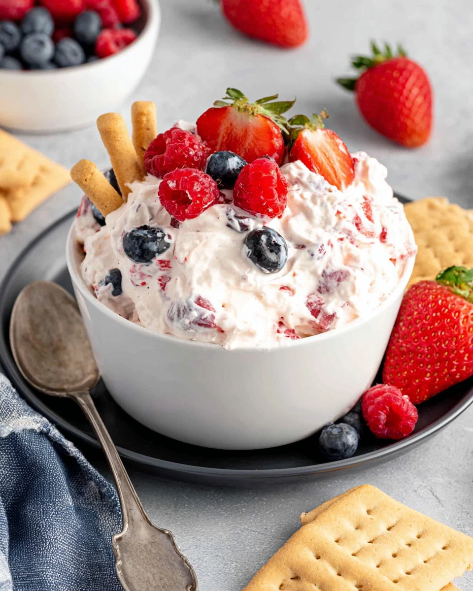 Berry cheesecake fluff with fresh berries and graham crackers in a white bowl