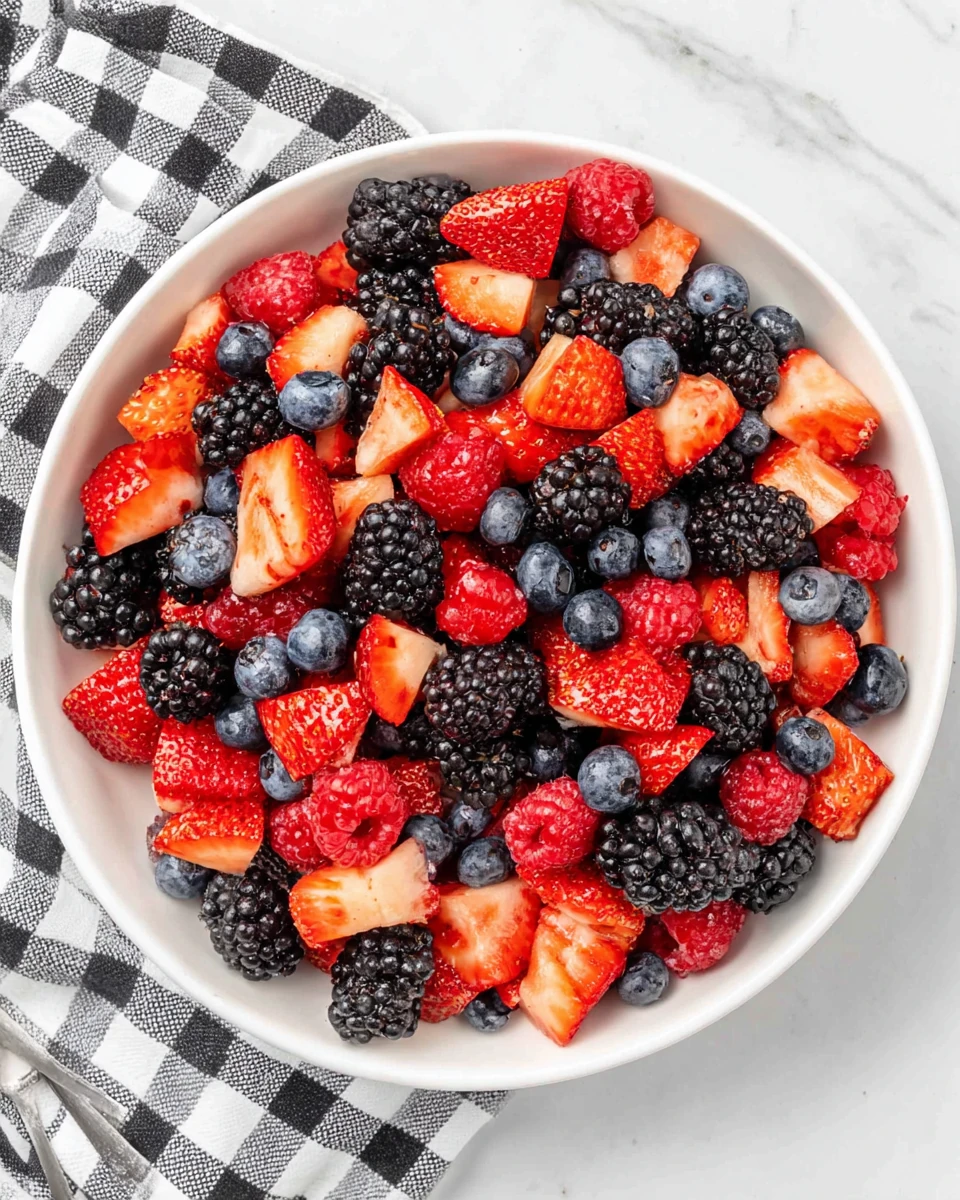 Colorful berry fruit salad with strawberries, blueberries, blackberries, and raspberries in a white bowl
