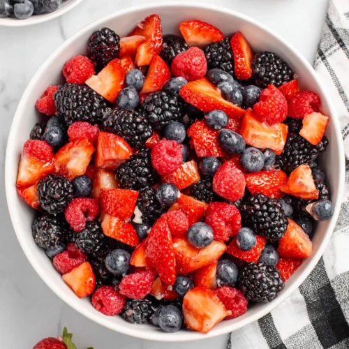 Colorful berry fruit salad with strawberries, blueberries, blackberries, and raspberries in a white bowl