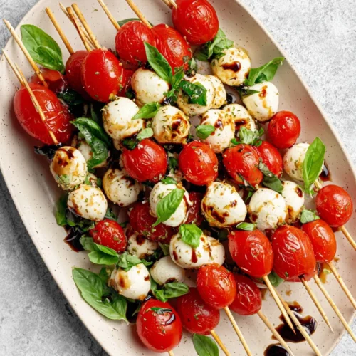 Caprese salad skewers with cherry tomatoes, mozzarella, and basil on a platter