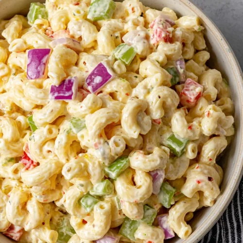 Classic macaroni salad with creamy dressing, red onion, celery, and bell pepper in a bowl