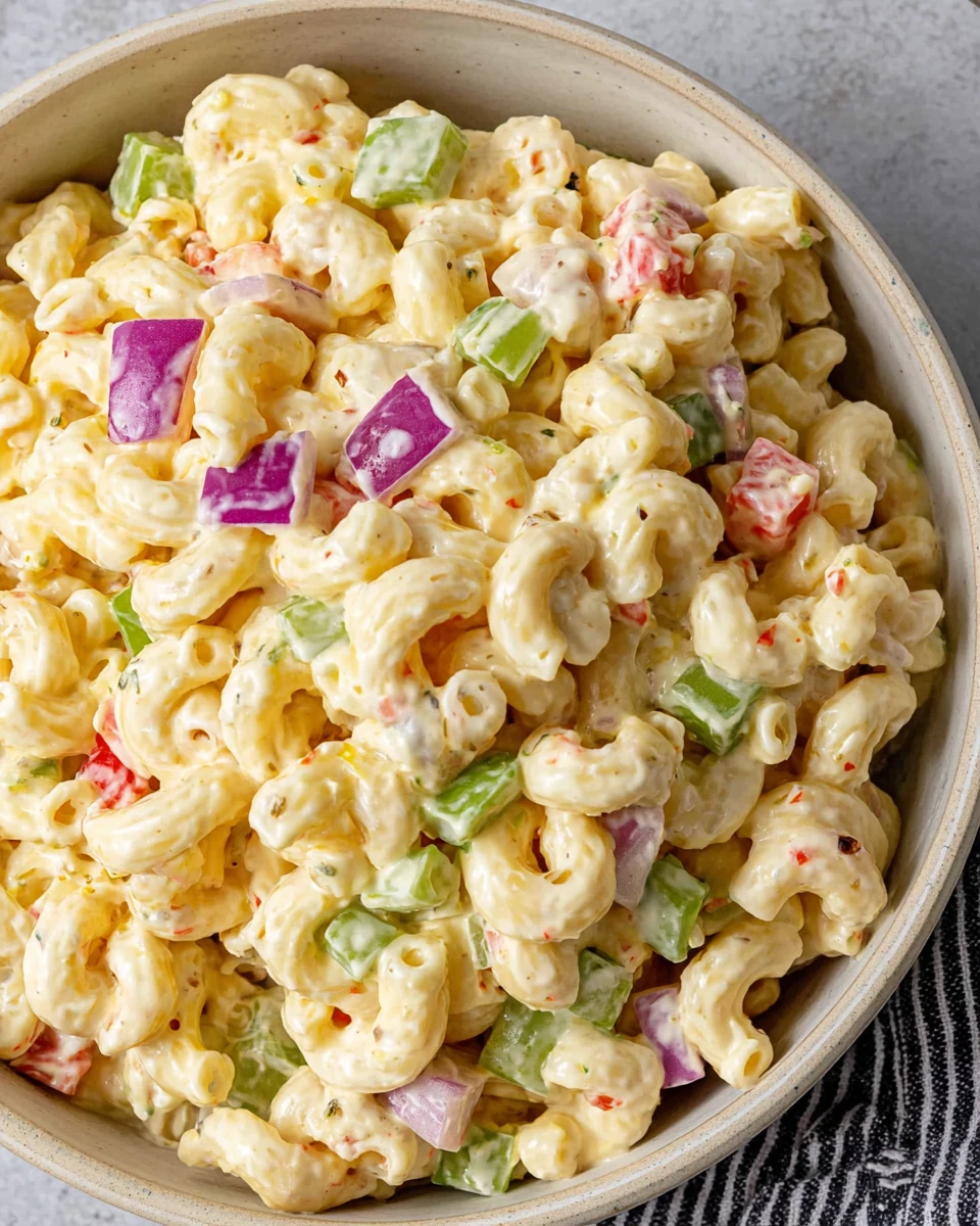 Classic macaroni salad with creamy dressing, red onion, celery, and bell pepper in a bowl