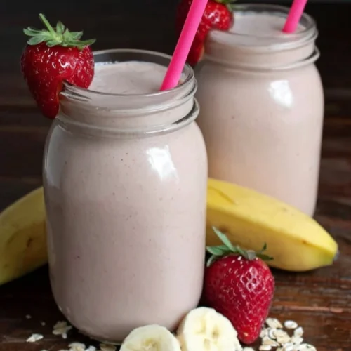 Creamy strawberry banana smoothie delight in glass jars with fresh fruit and oats
