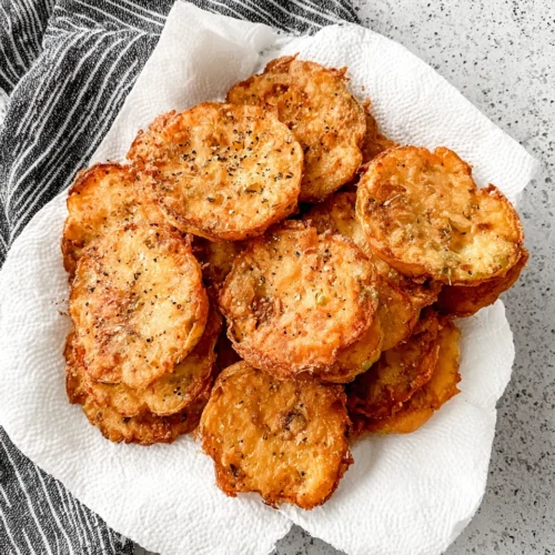 Crispy fried yellow squash rounds on paper towel, golden brown and seasoned