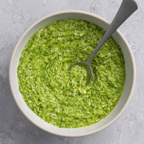 Fresh garlic scape pesto in a bowl with spoon, vibrant green sauce