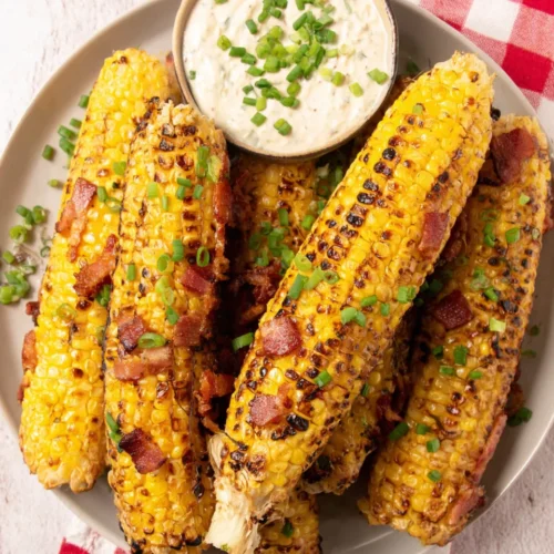 Grilled corn ribs with bacon and ranch dip on a white plate