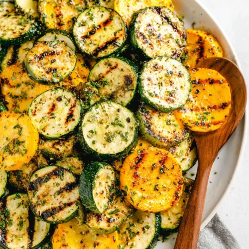 Grilled zucchini and squash slices with char marks on a white plate