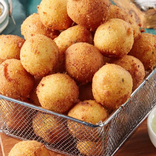 Delicious Honey Corn Hush Puppies You’ll Love 1 Crispy honey corn hush puppies in a wire basket and bowl with dipping sauce