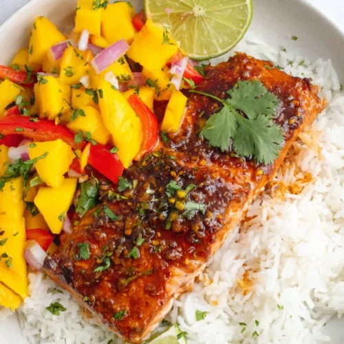 Honey lime salmon with mango salsa on rice, garnished with lime