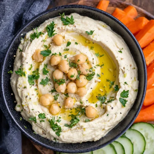 Creamy hummus without tahini in a black bowl with olive oil and herbs