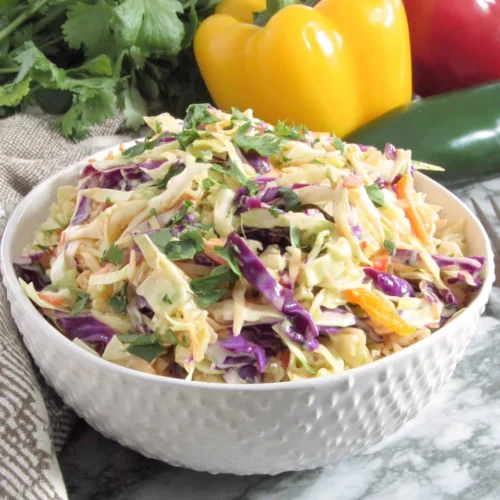 Mexican Coleslaw: A Flavorful and Quick Side Dish 1 Fresh Mexican coleslaw with red cabbage and bell peppers in a white bowl