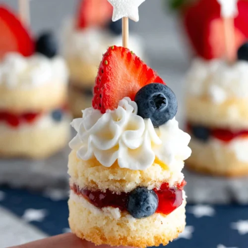 Mini strawberry shortcake bite with strawberry, cream, and blueberry on star-patterned paper