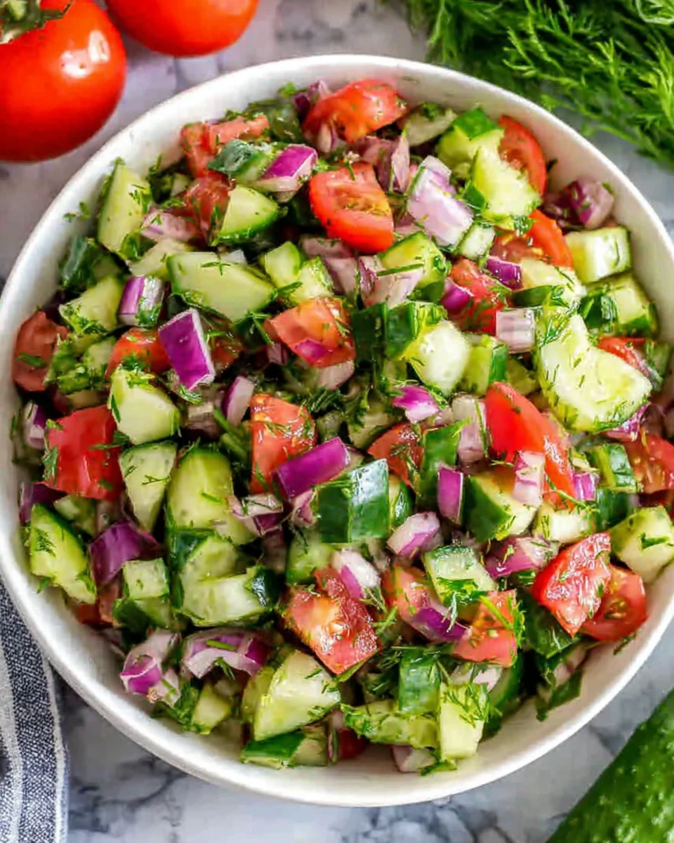 Quick Italian cucumber salad with fresh tomatoes, red onions, and herbs in a white bowl