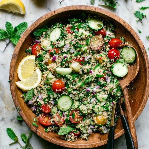 Quinoa tabbouleh salad with fresh herbs, tomatoes, and cucumbers in a wooden bowl