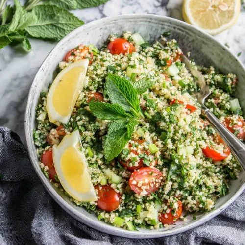 Quinoa tabouli salad with fresh herbs, tomatoes, and lemon in a ceramic bowl