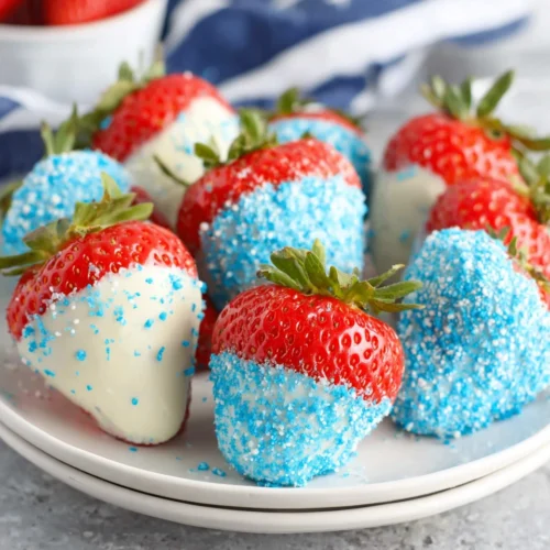 Red white & blue chocolate-covered strawberries with blue sugar on a white plate